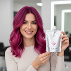 Woman with vibrant pink hair holding a hair color mask product package in a salon setting